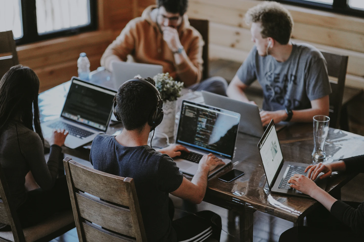 Equipo colaborando en una mesa de trabajo con computadores